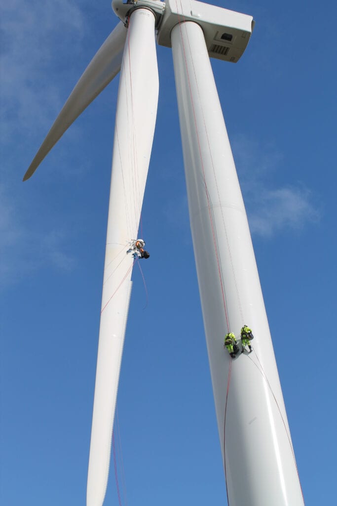 Workers hanging from a wind turbine.